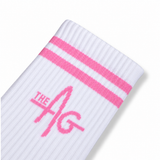 A close-up of a white ribbed sock with two pink stripes near the top and a pink 'THE AG' logo on the side, shown on a white background.