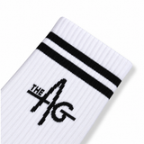 A close-up of a white ribbed sock with two bold black stripes near the cuff and a black 'THE AG' logo on the side, shown against a clean white background.