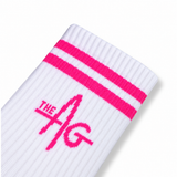 A close-up of a white ribbed sock with two bright pink stripes near the cuff and a pink 'THE AG' logo printed on the side, shown on a clean white background.